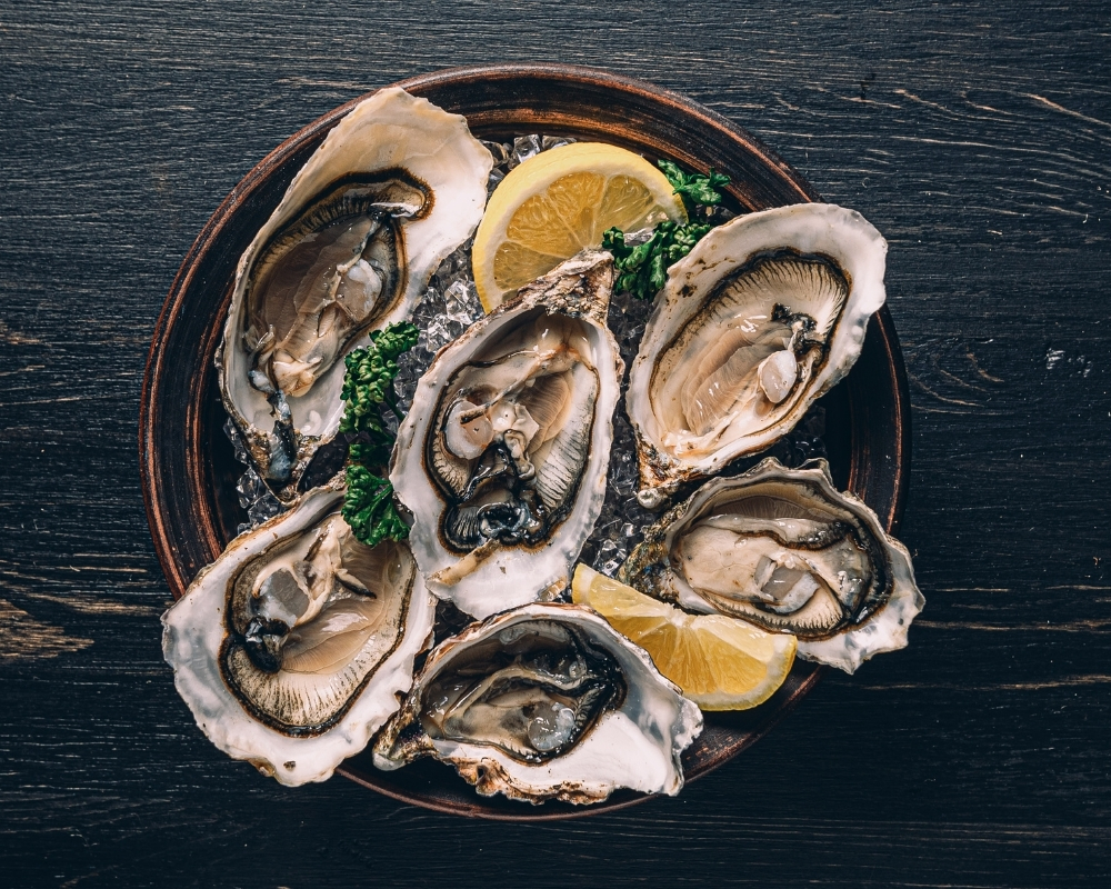 Six fresh oysters on ice with lemon garnish at 21 Raw Bar Taphouse & Grill，a Seafood Restaurant in Greenville