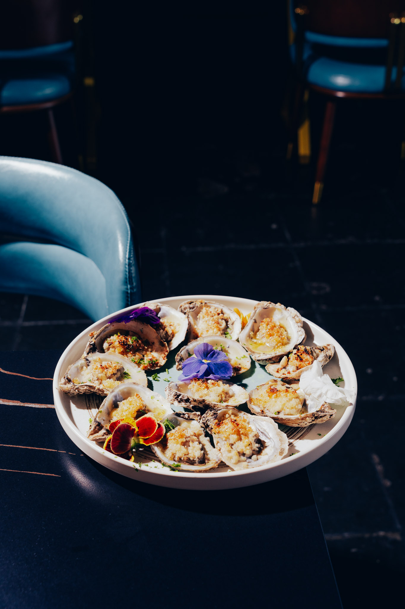 Baked oysters topped with garlic crumbs and edible flowers