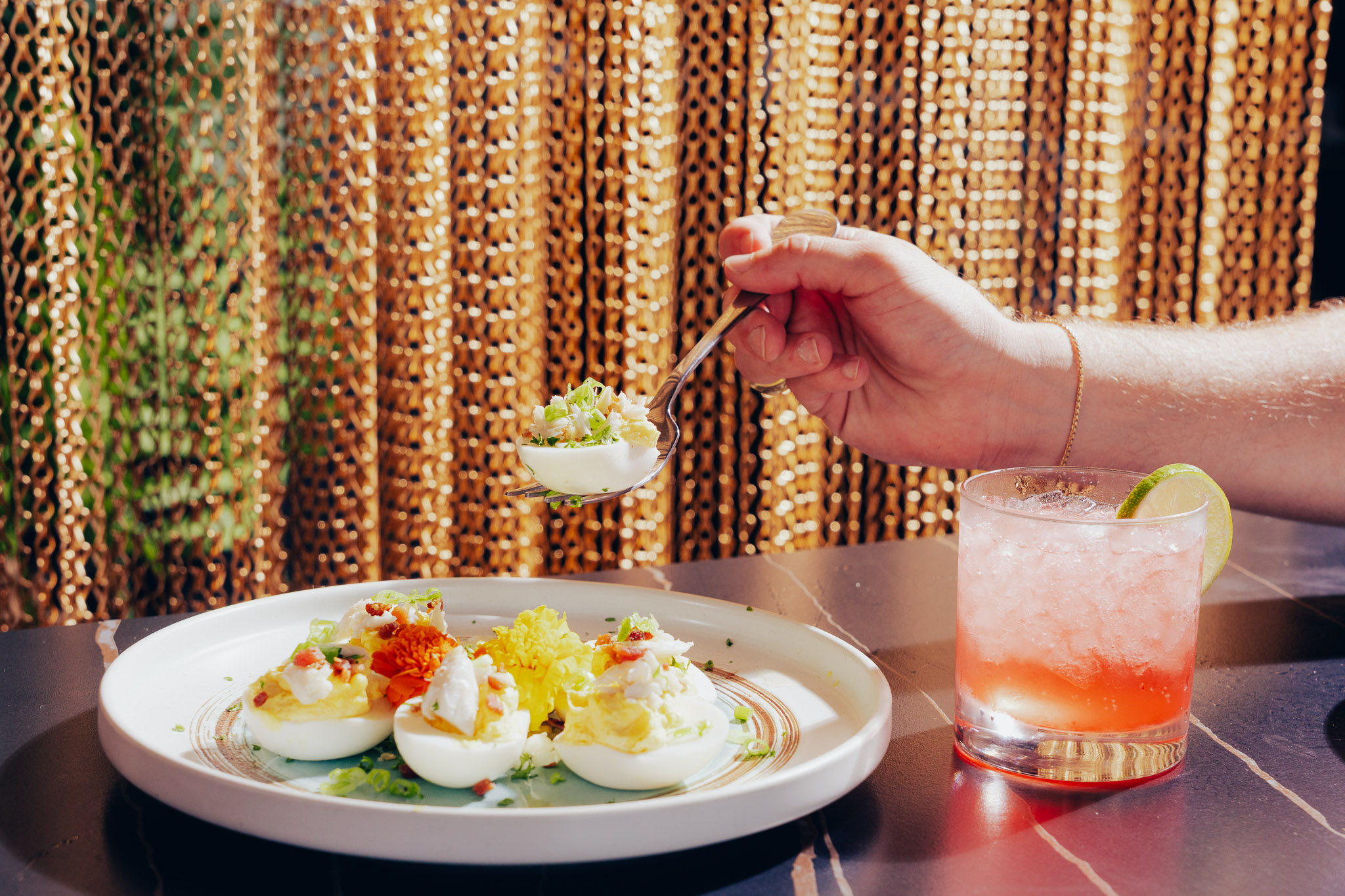 Deviled eggs served with pink cocktail and golden chain backdrop