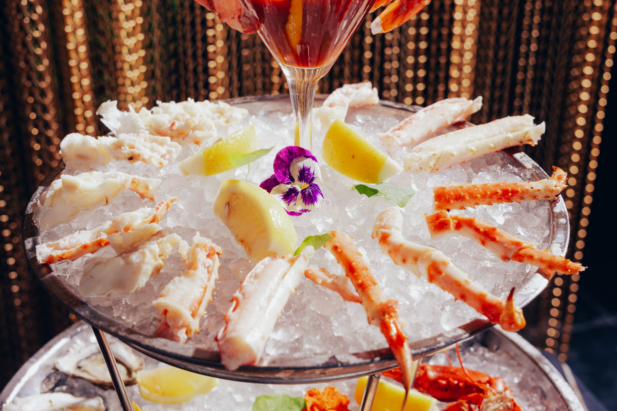 Iced king crab legs with lemon wedges and edible flowers