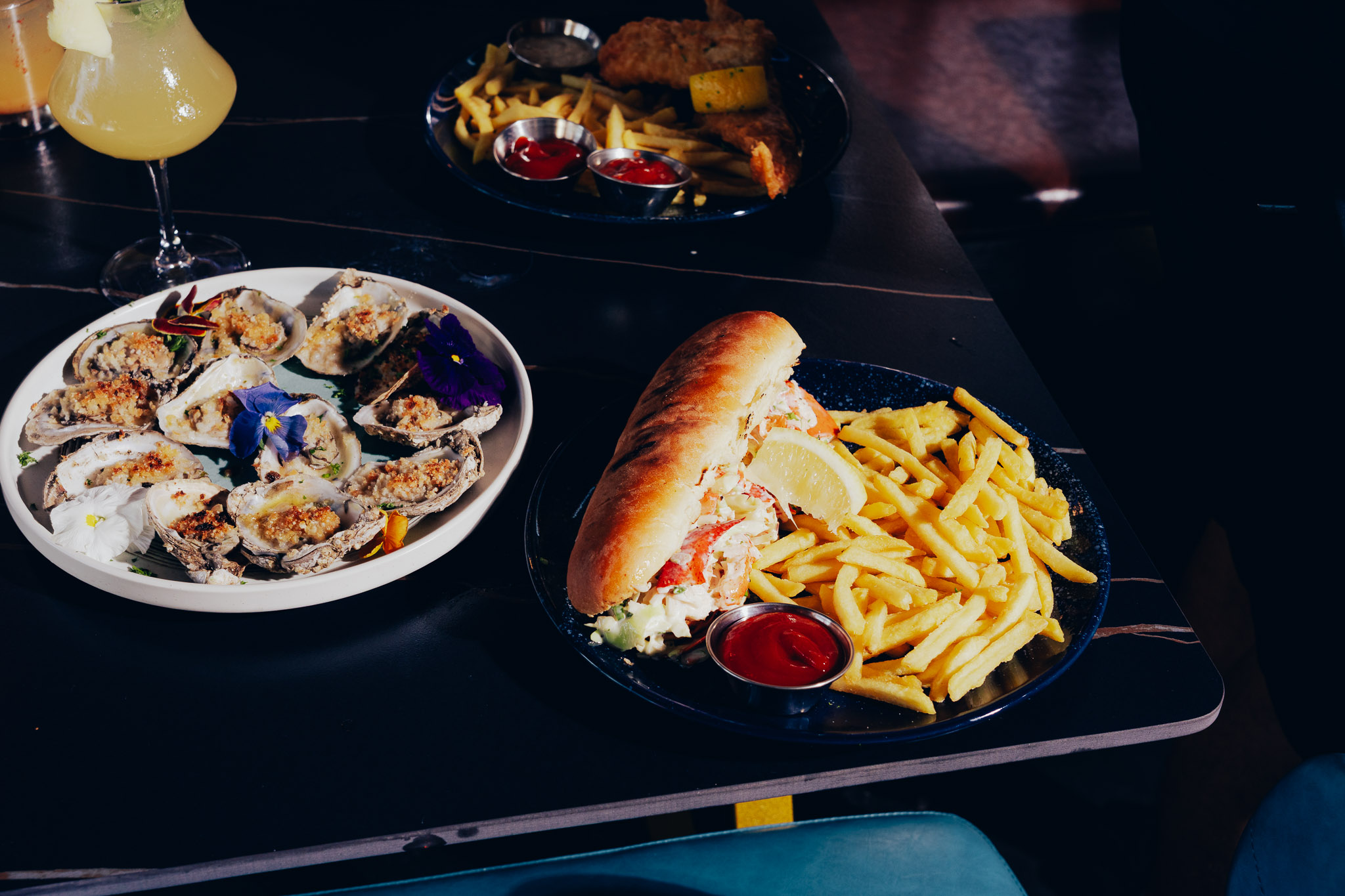 Seafood feast with oysters, lobster roll, fish chips and cocktails