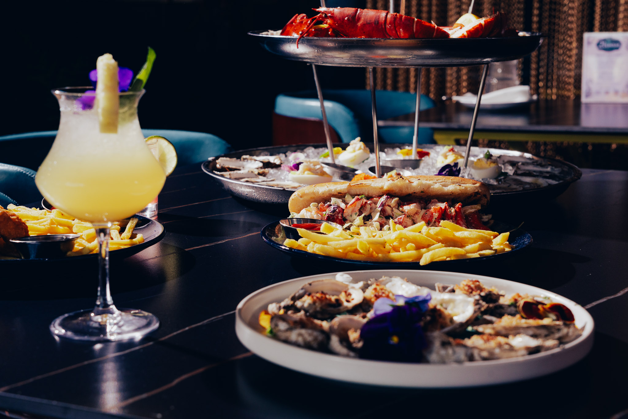 Seafood platter, lobster roll and fruity cocktail on dark table