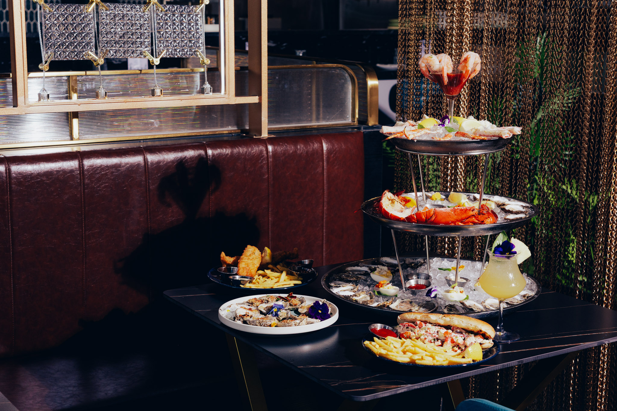 Three-tier seafood tower with assorted dishes in restaurant booth