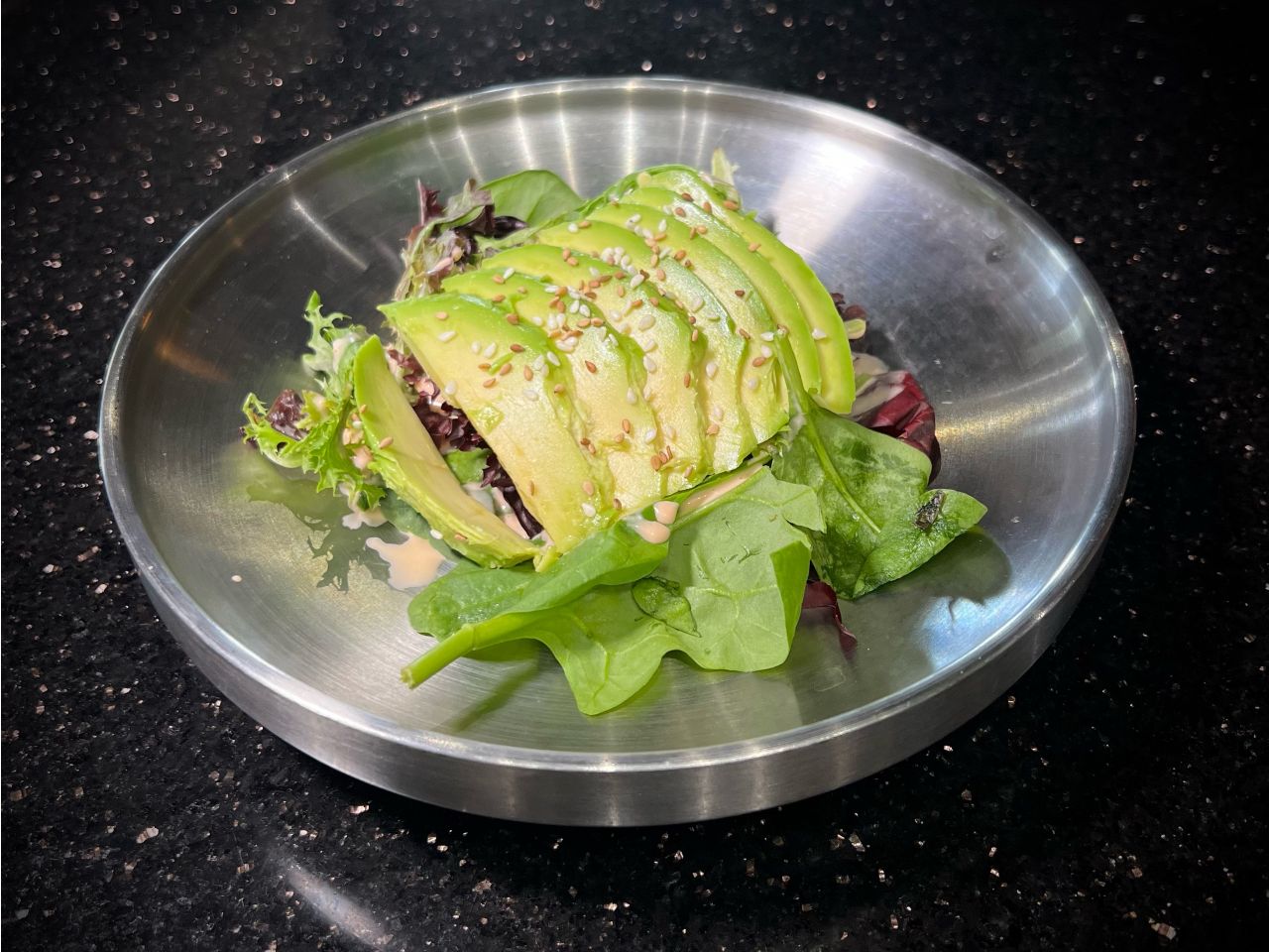 Fresh avocado salad mixed with crisp leafy greens on metal plate at 592 Korean BBQ, an Asian Fusion Restaurant in Appleton