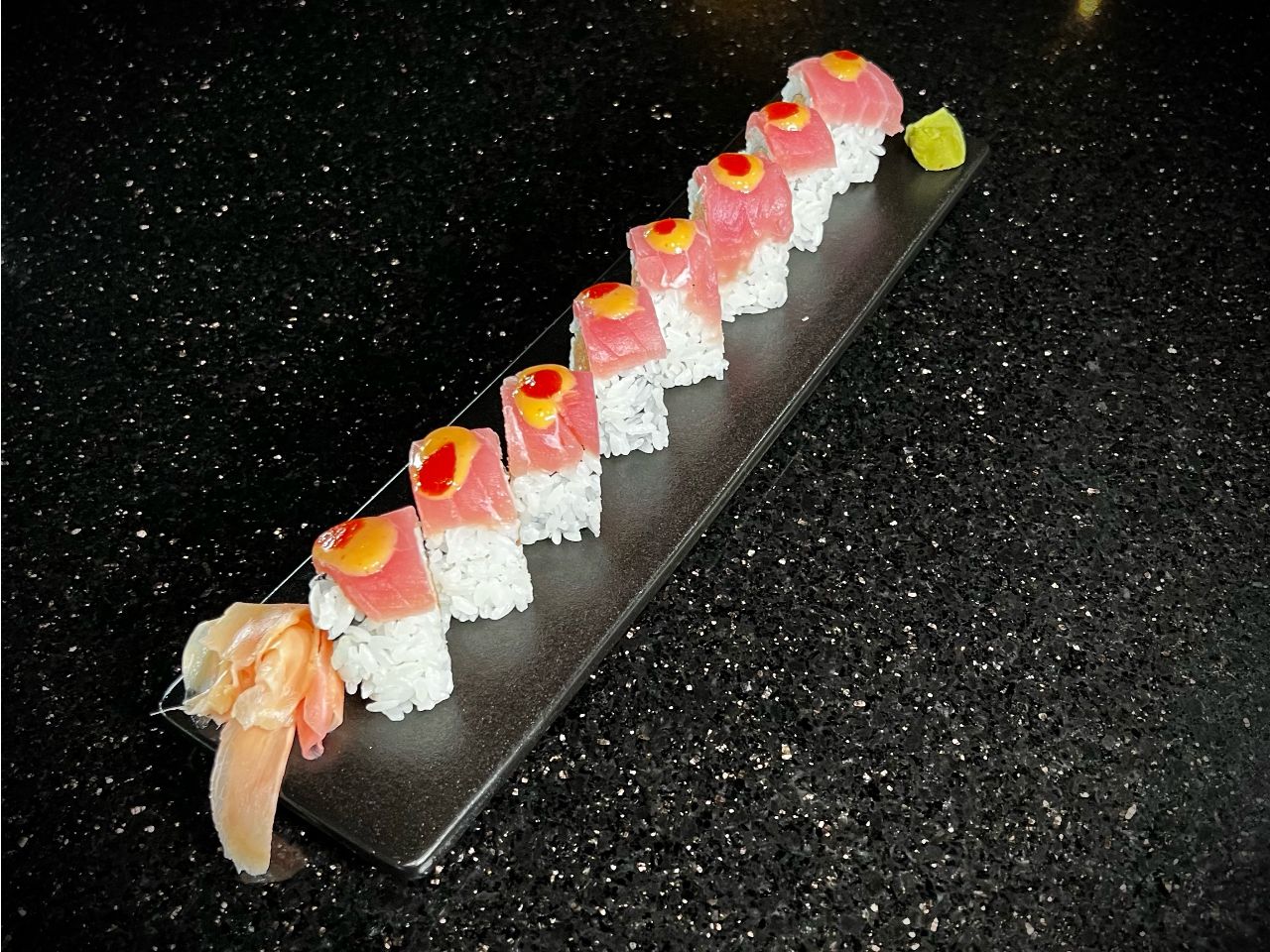 Crazy tuna sushi roll with fresh tuna and assorted toppings on black counter at 592 Korean BBQ, an Asian Fusion Restaurant in Appleton