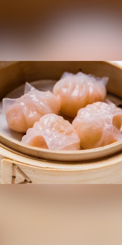Four translucent shrimp dumplings in a bamboo steamer basket.