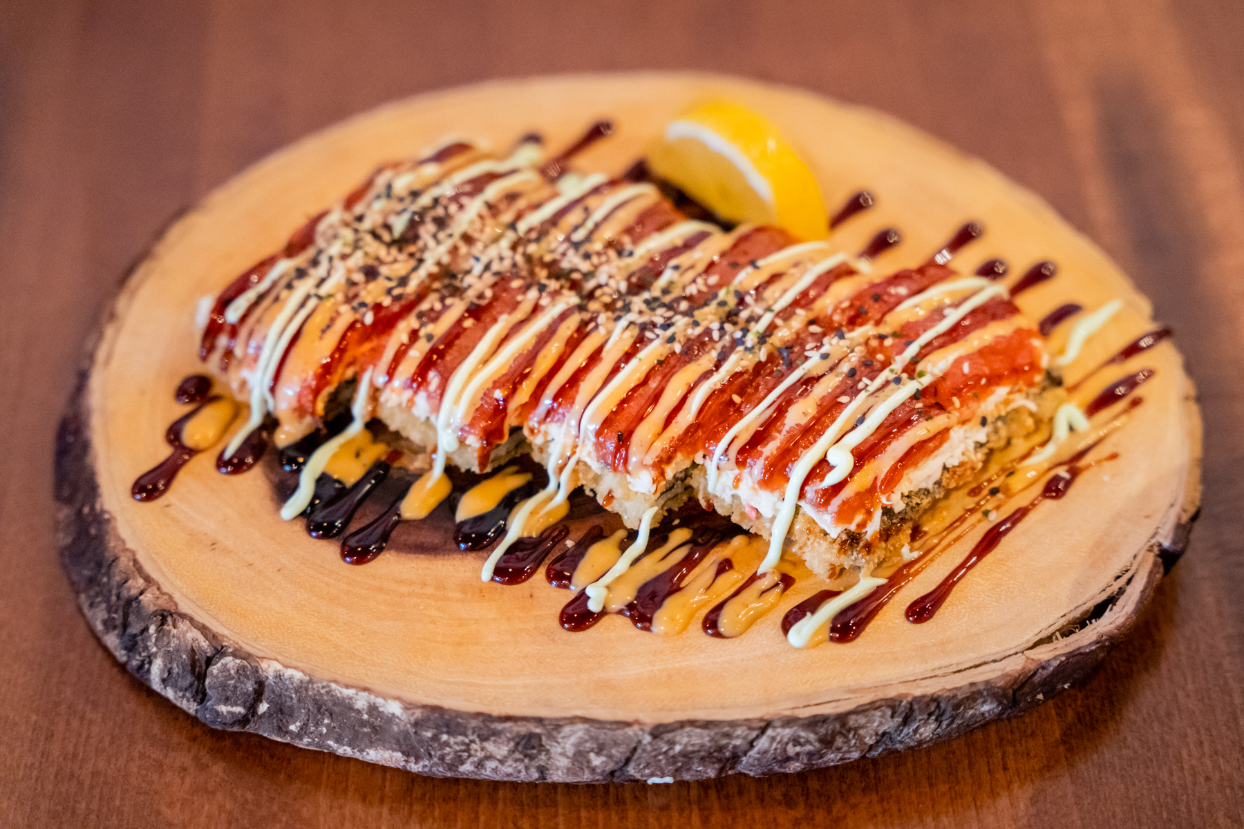 Crispy tempura roll with drizzled sauces at Aji Izakaya Cypress, a Japanese Restaurant in Cypress