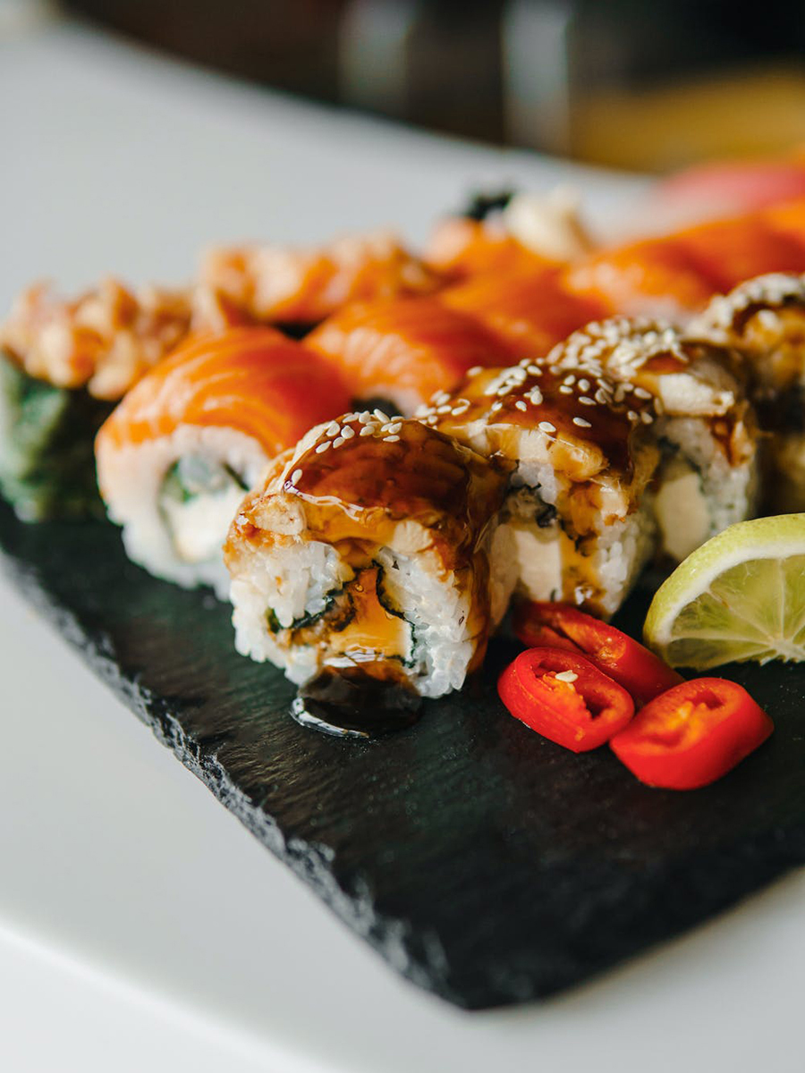 Assorted sushi rolls served on black slate plate