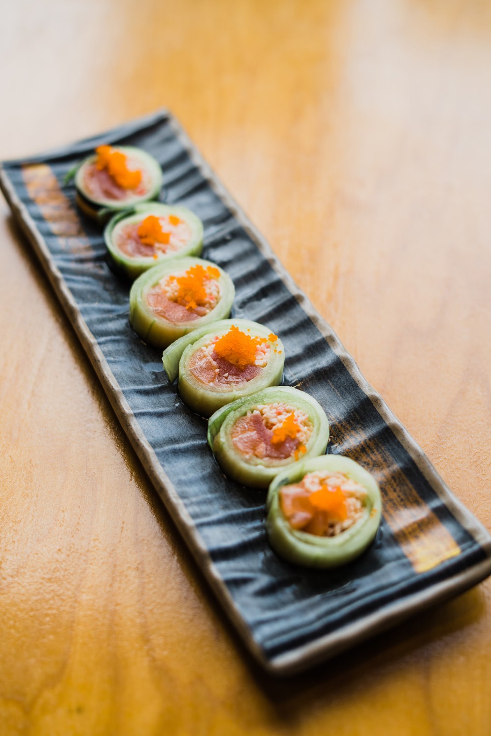 Thin cucumber rolls filled with fish and tobiko on top