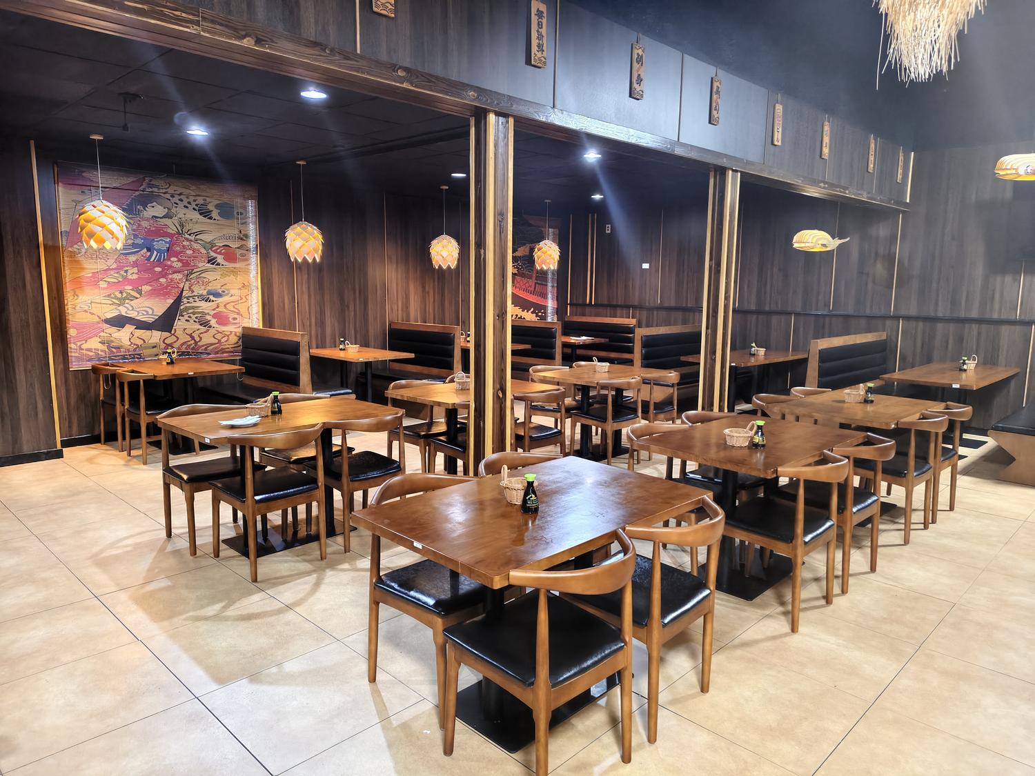 Japanese-themed restaurant interior with dark wood paneling, decorative lights, and mural art.