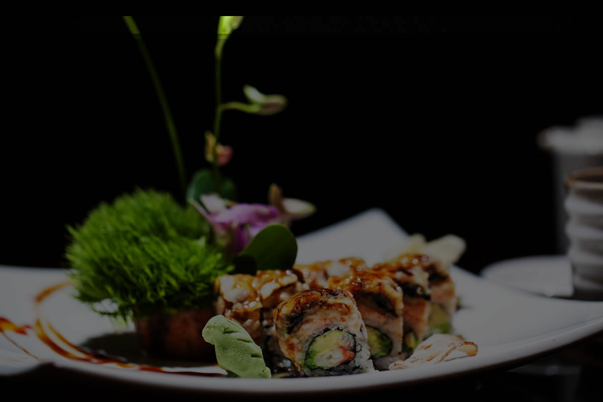 Gourmet sushi roll plated with decorative green moss, purple orchid and drizzled savory sauce at Akira, a Japanese Restaurant in Glenmont