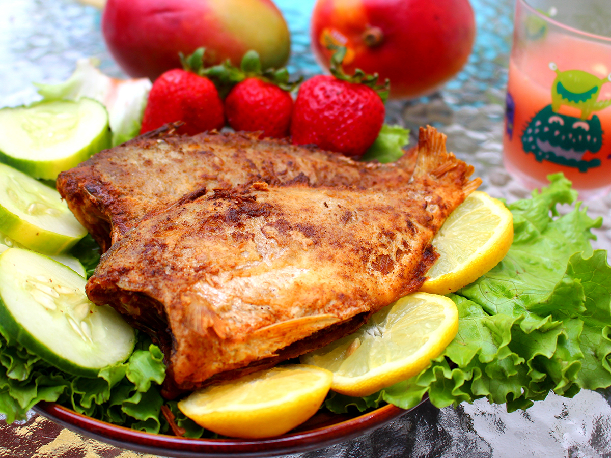 Crispy pan‑fried fish served with lemon slices, lettuce and fresh fruits on decorated plate at Aki Sushi & Asian Fusion, a Sushi Restaurant in Port Washington