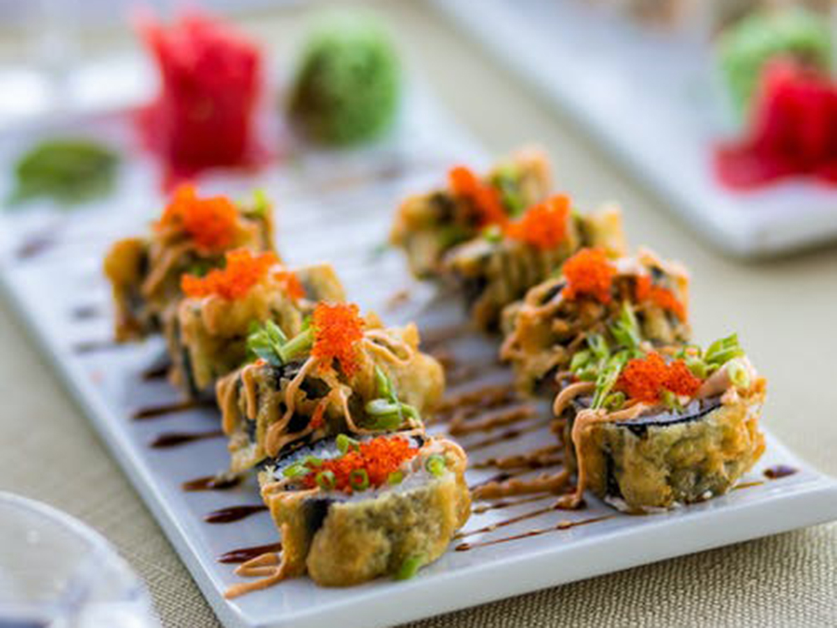 Crispy tempura sushi rolls topped with orange fish roe on white plate at Aki Sushi & Asian Fusion, a Sushi Restaurant in Port Washington