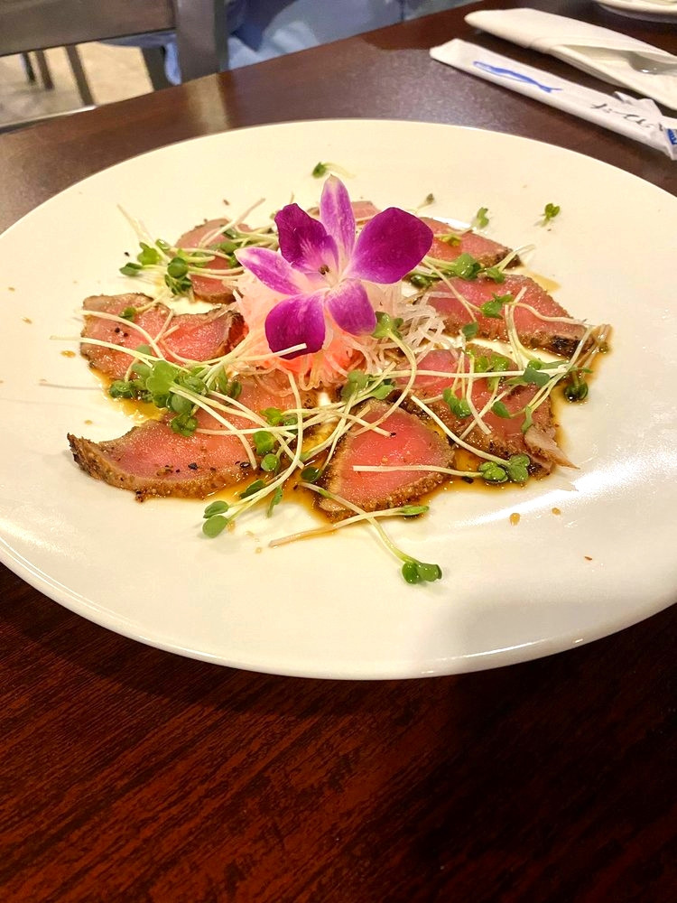 Seared tuna slices with microgreens and sauce, garnished with orchid at Ako Sushi & Seafood, a Japanese Restaurant in Titusville