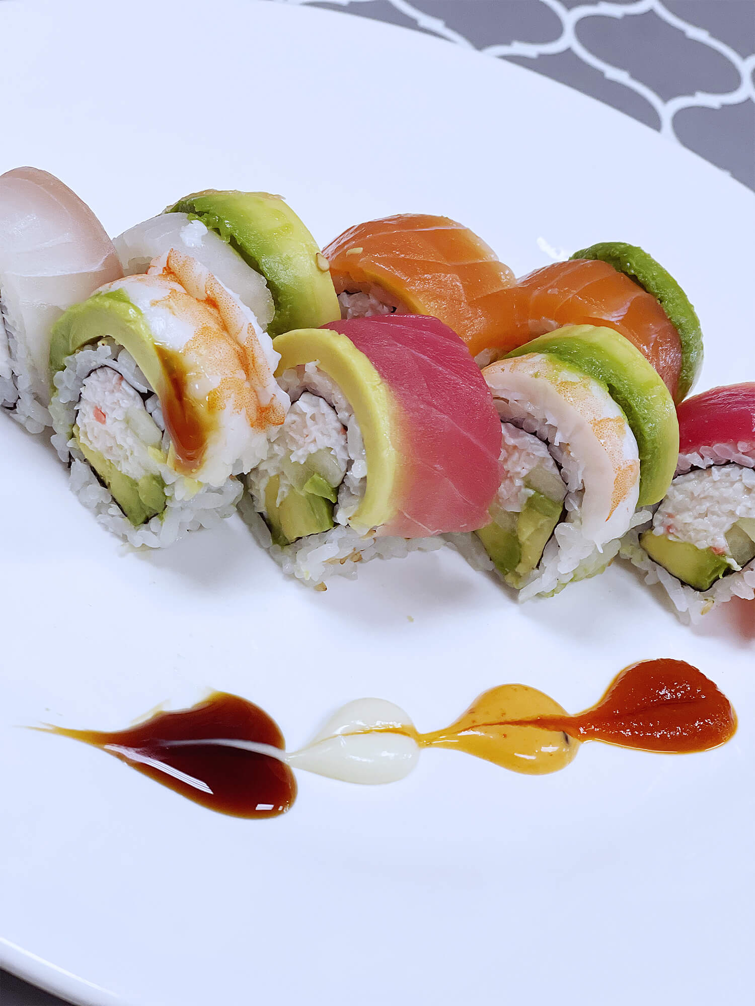 Sushi platter with various fresh fish, avocado, and colorful sauces at Aloha Hawaiian BBQ & Sushi, a Asian Fusion restaurant in Baldwin Park