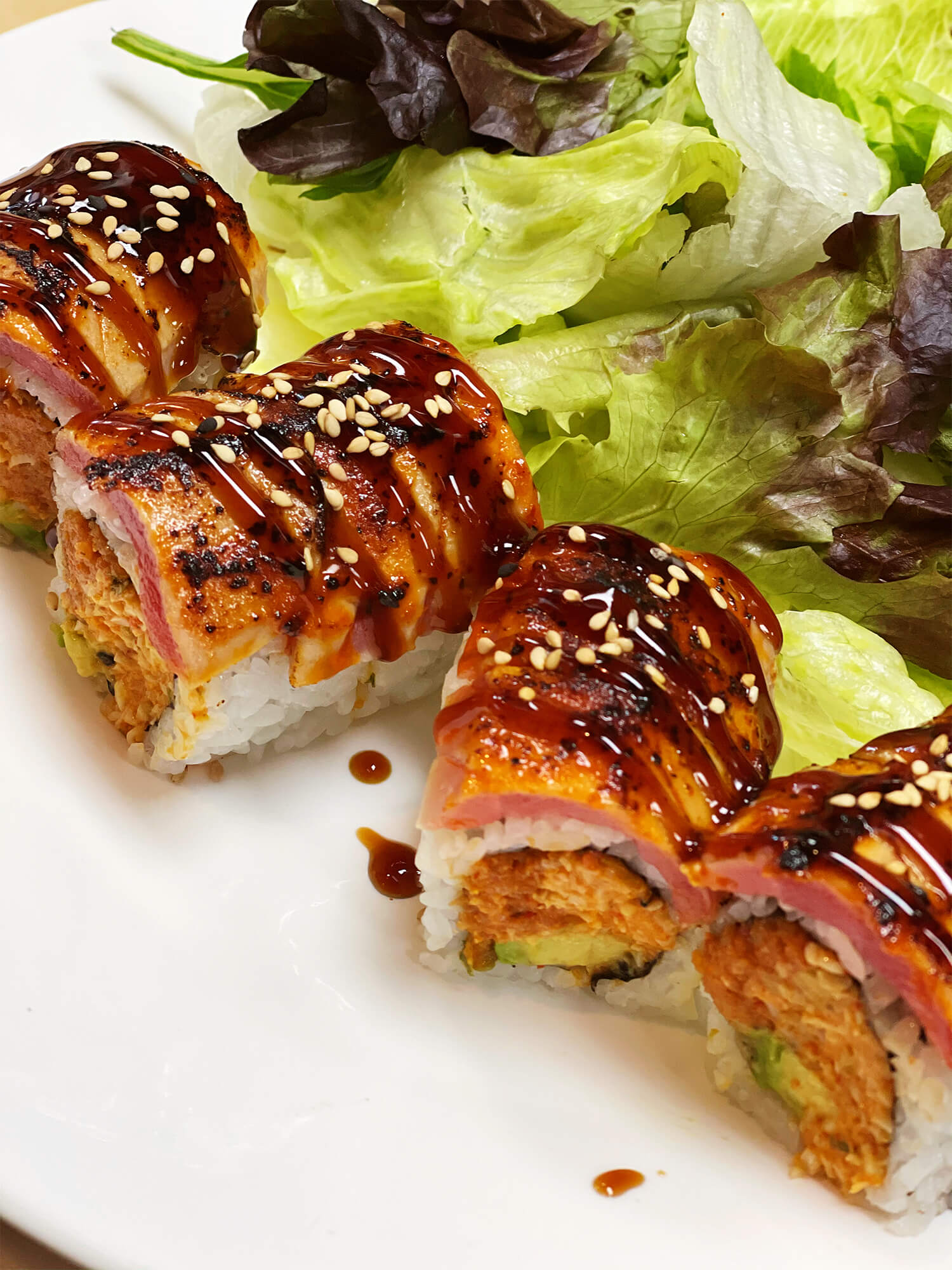Sushi roll with seared salmon, sesame seeds, and sauce at Aloha Hawaiian BBQ & Sushi, a Asian Fusion restaurant in Baldwin Park