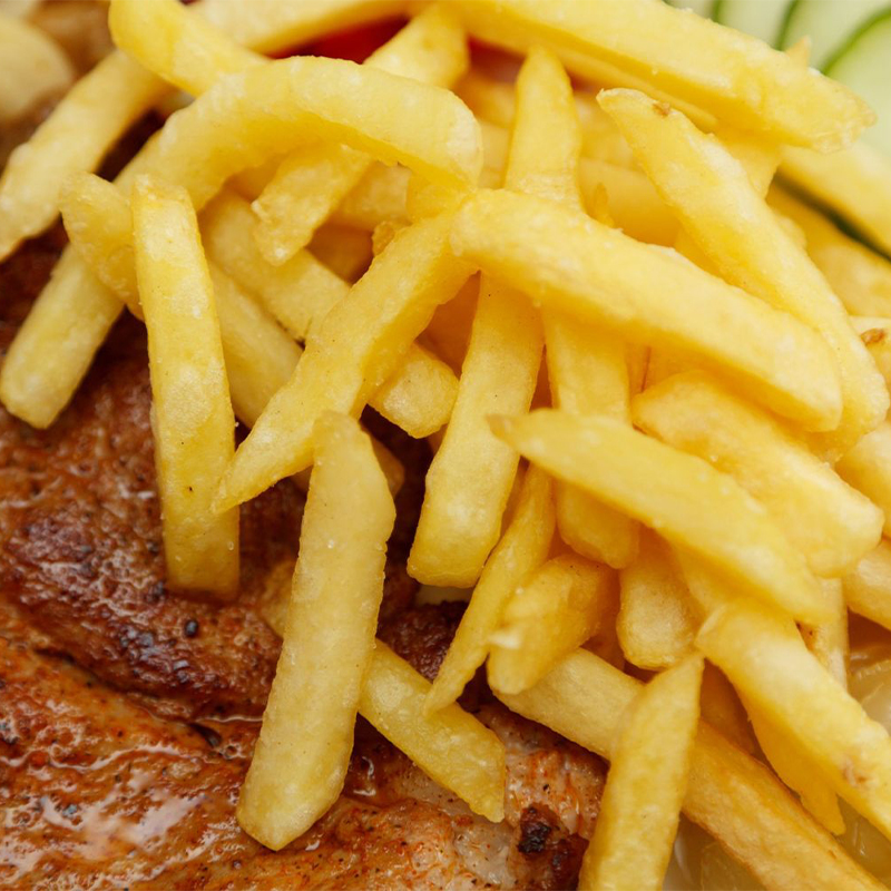 A close-up view of crispy golden french fries served over a grilled meat cutlet at American wing express, a fast food restaurant in Columbus
