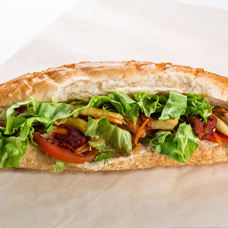 A long submarine sandwich filled with fresh lettuce, sliced tomatoes, carrots, and grilled meat at American wing express, a fast food restaurant in Columbus