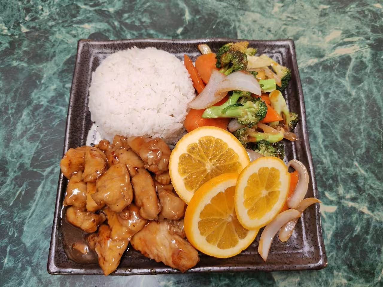 Teriyaki chicken rice plate garnished with orange slices and mixed vegetables at Asia Hibachi & Rice Bowls，an Asian Fusion Restaurant in Buffalo