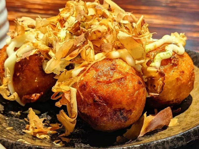 Saigon-Bistro-Vietnamese-Restaurant-Japanese-Takoyaki-Savannah Golden-brown takoyaki balls topped with bonito flakes and sauce.