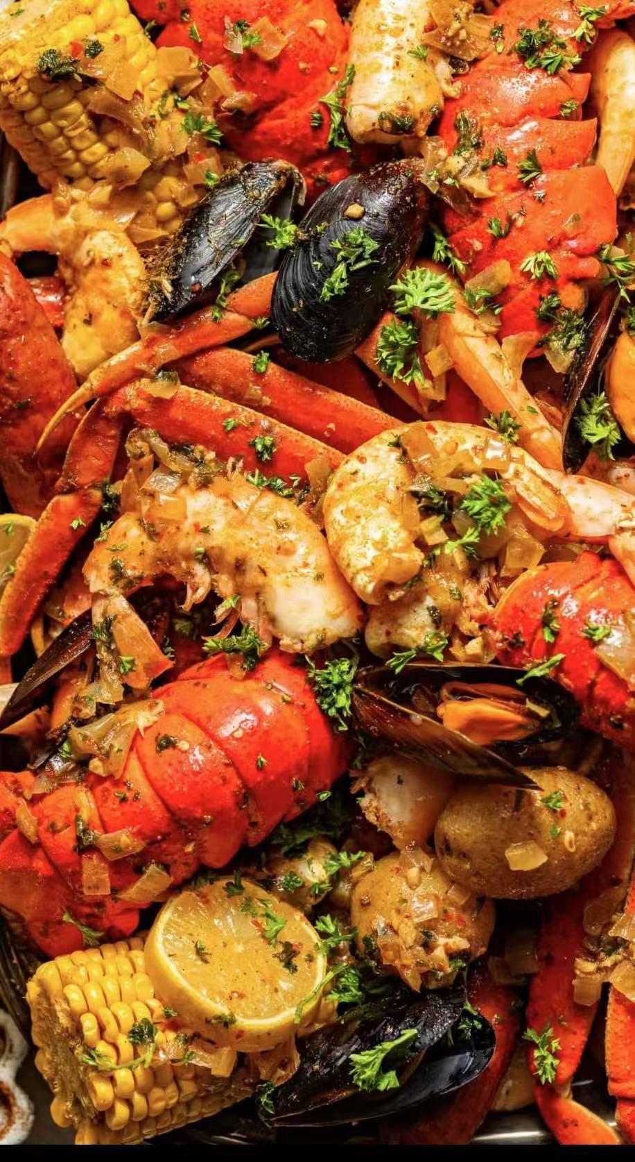 Seafood platter with lobster, shrimp, mussels, corn, potatoes, and lemon garnish