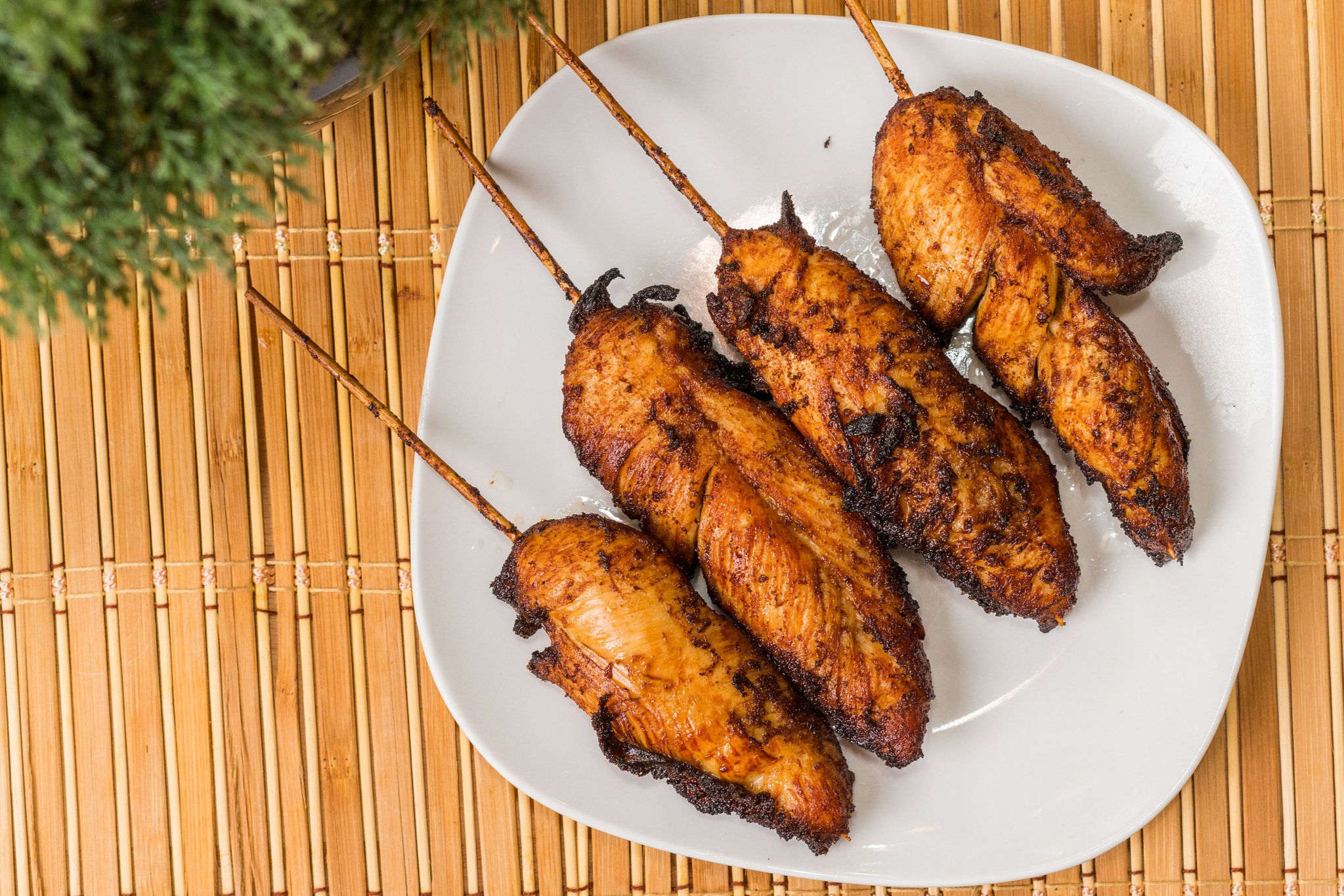 Grilled chicken skewers served on a white square plate