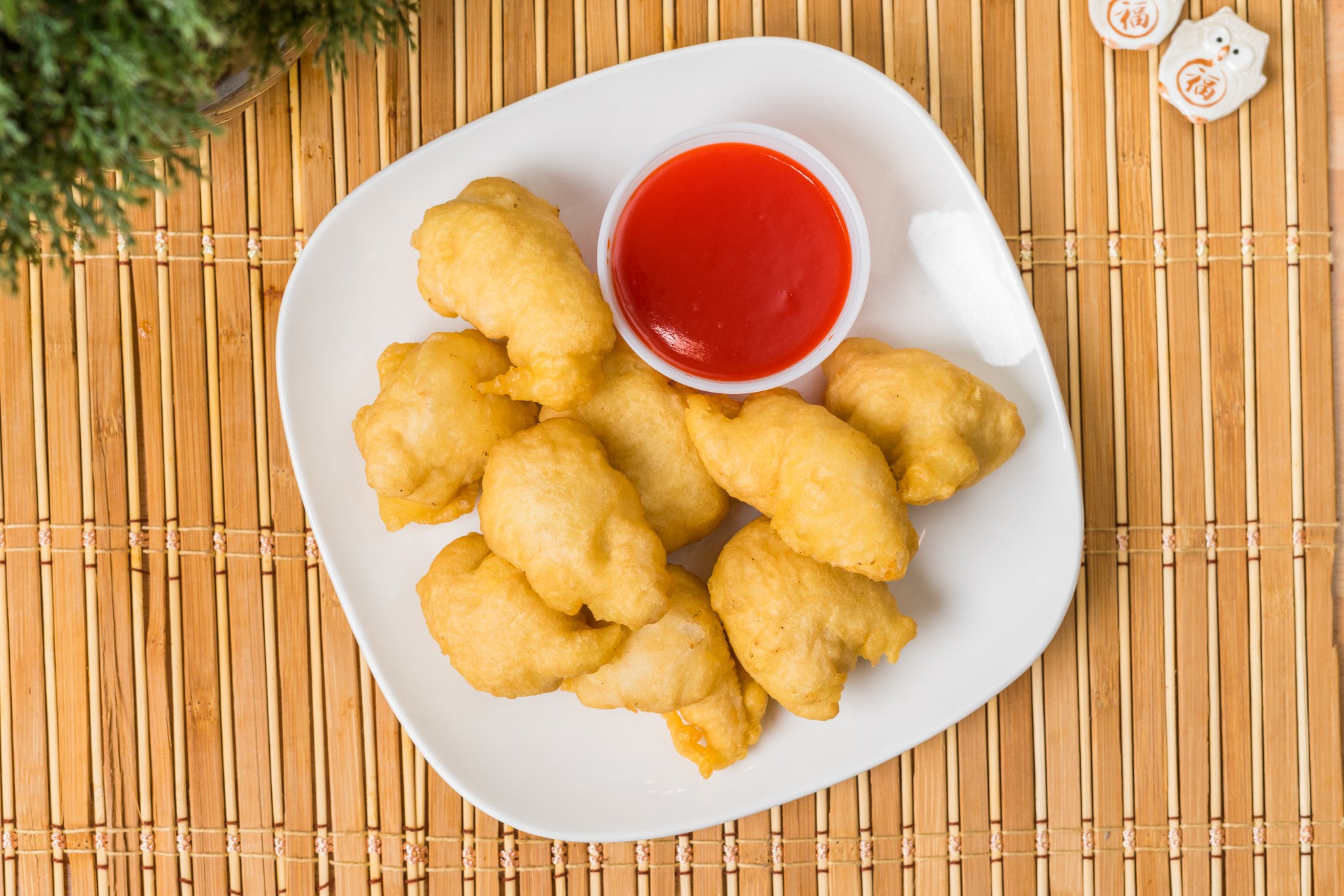 Sweet and sour chicken pieces with bright red dipping sauce
