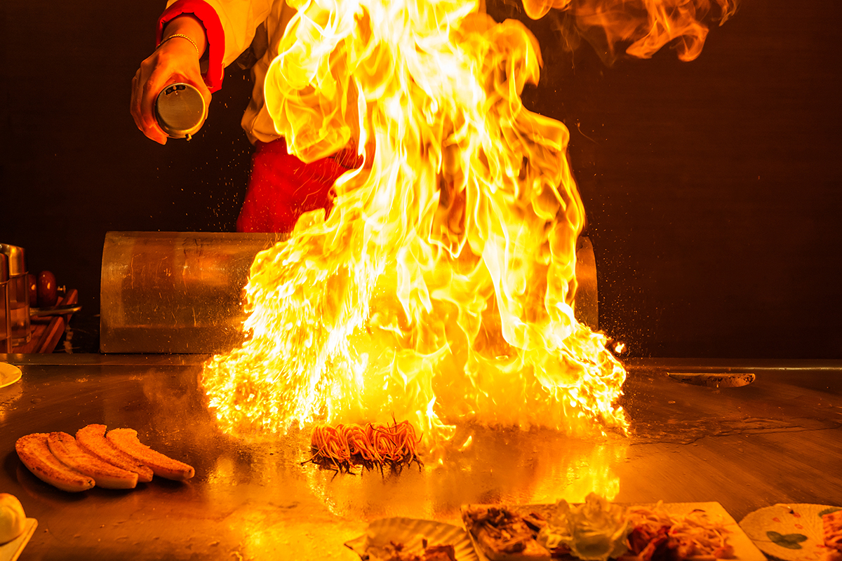 Dramatic hibachi flame show cooking on teppan grill at Asuka, an Asian Fusion Restaurant in Bloomington
