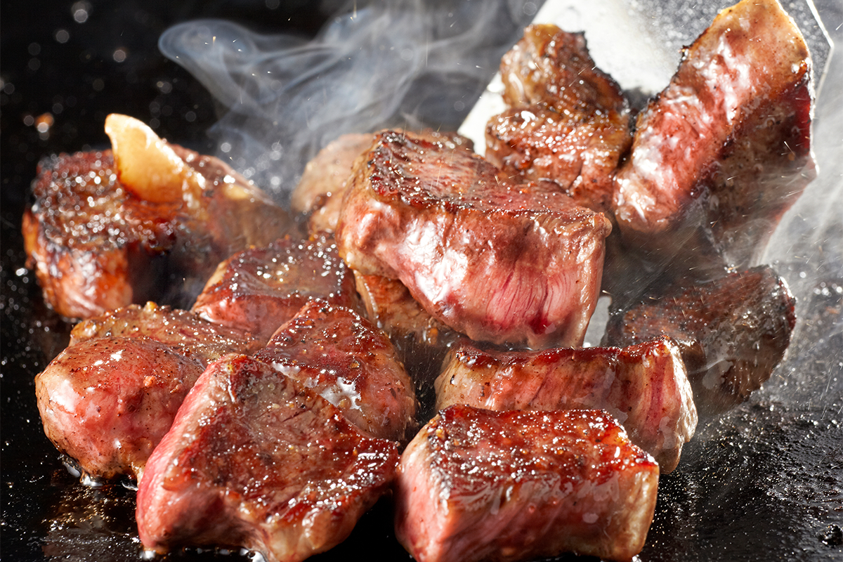 Sizzling hibachi steak cubes cooking on teppan grill at Asuka, an Asian Fusion Restaurant in Bloomington