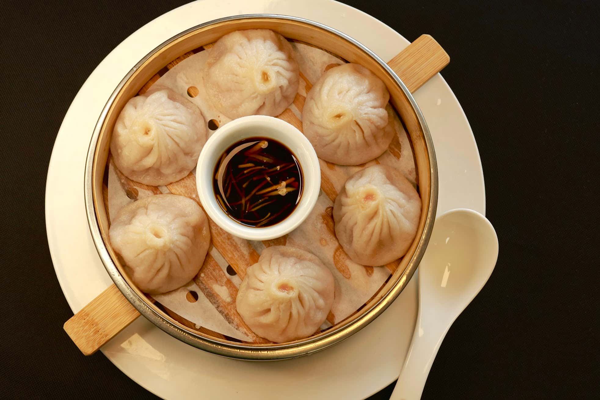Steamed pork soup dumplings served with soy sauce at Bao House, a Chinese Restaurant in Stillwater