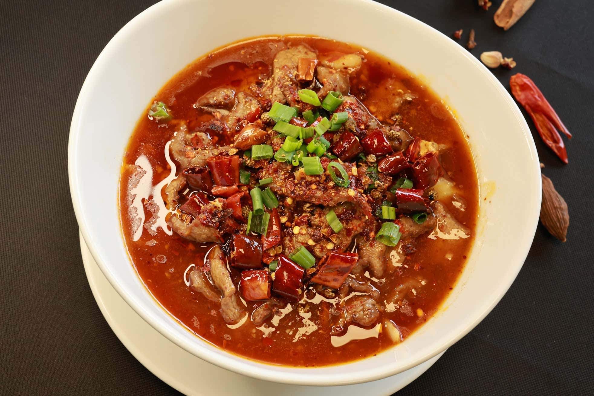 Spicy boiled beef in chili broth topped with green onions at Bao House, a Chinese Restaurant in Stillwater