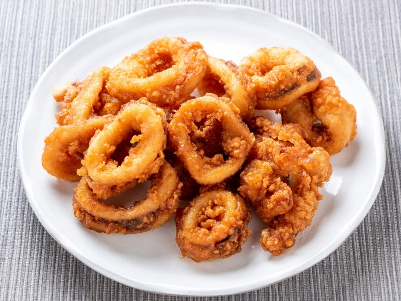 Crispy golden fried squid rings served on a white plate at Bayou Crab, a Seafood Restaurant in Lake Jackson