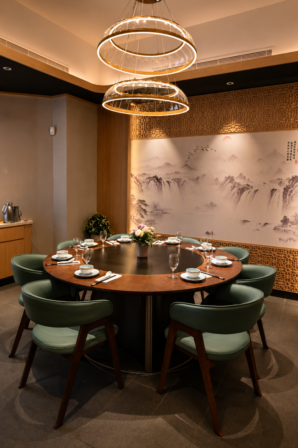Elegant private dining room with a round table, green chairs, modern lighting, and Chinese landscape art