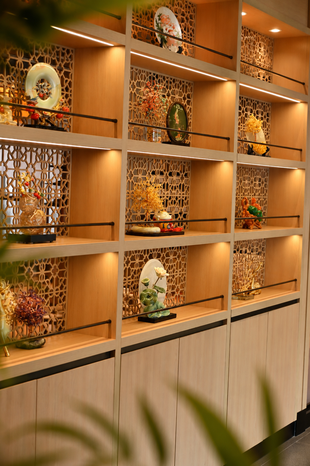 Warm wooden display shelves featuring decorative art and ornaments in a refined restaurant interior