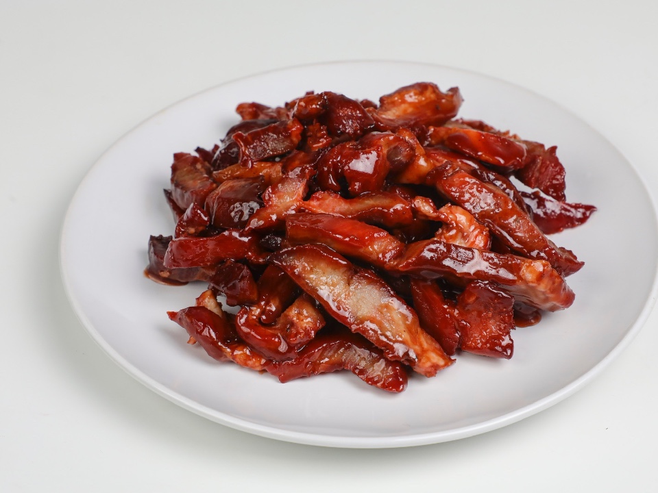 Dark red glazed meat strips on a white plate