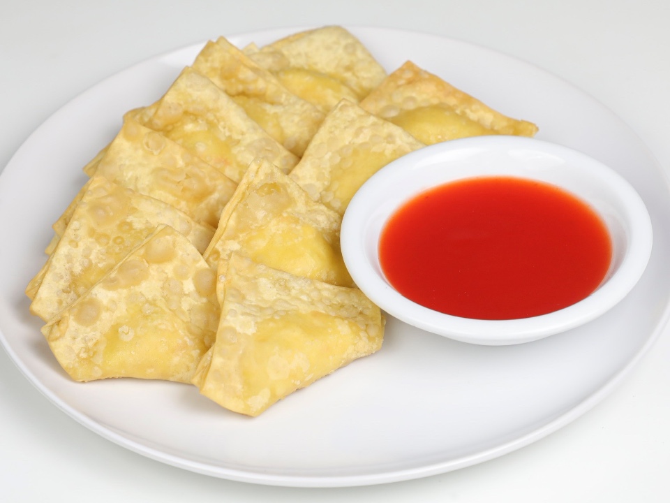 Fried wonton chips with red dipping sauce on a white plate