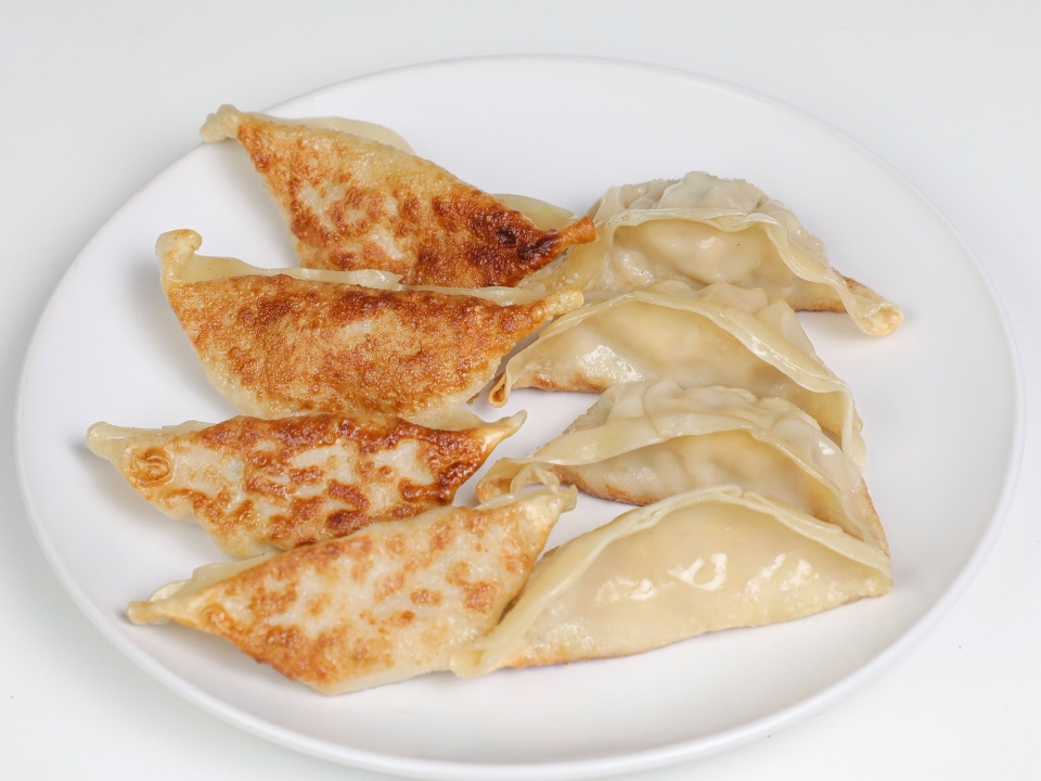 Pan-fried dumplings arranged on a white plate