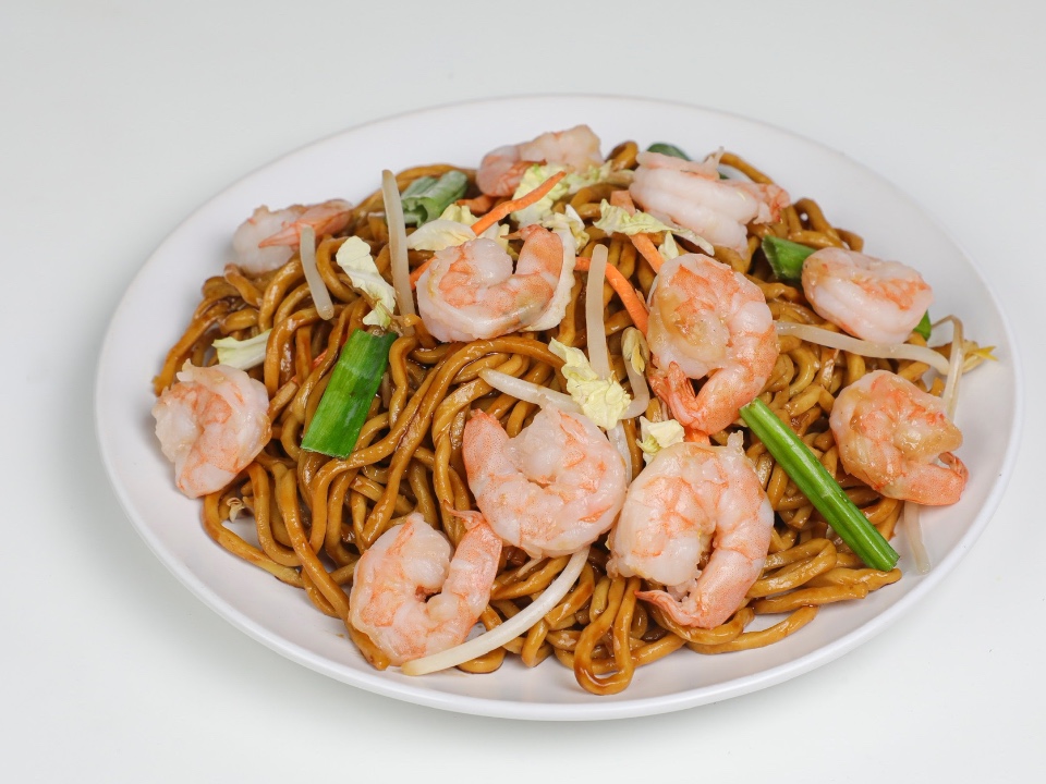 Stir-fried noodles with shrimp, cabbage, and carrots on a white plate