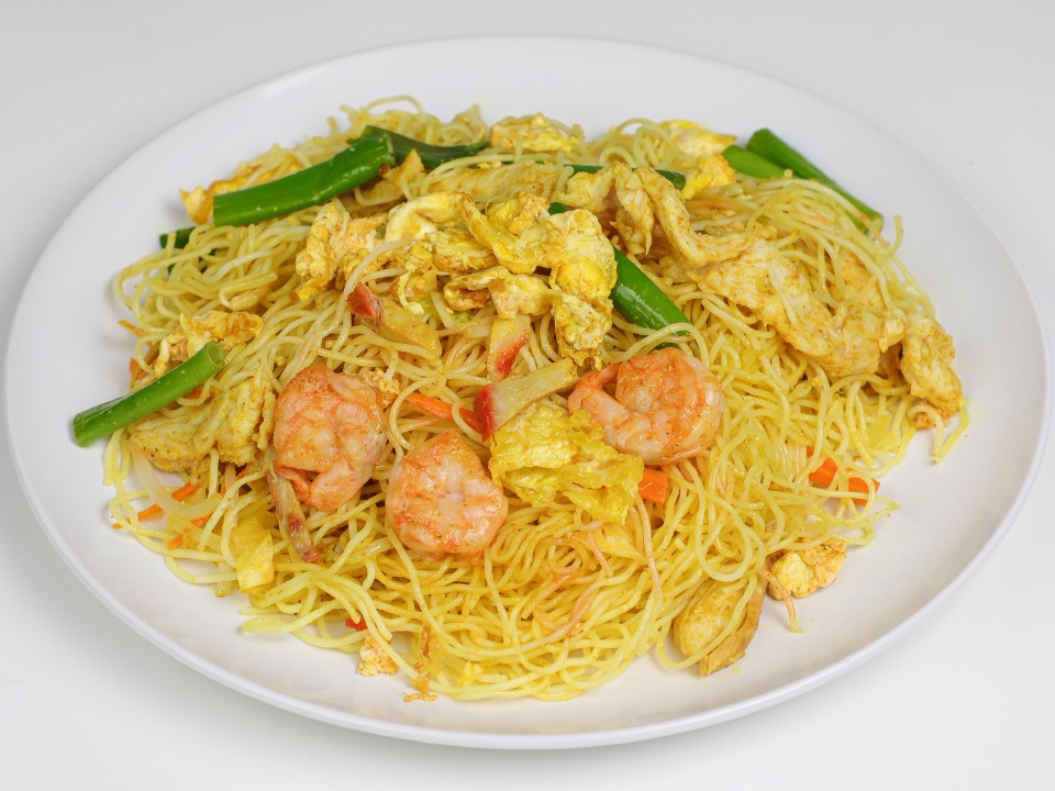Thin noodles with shrimp, egg, and green beans on a white plate