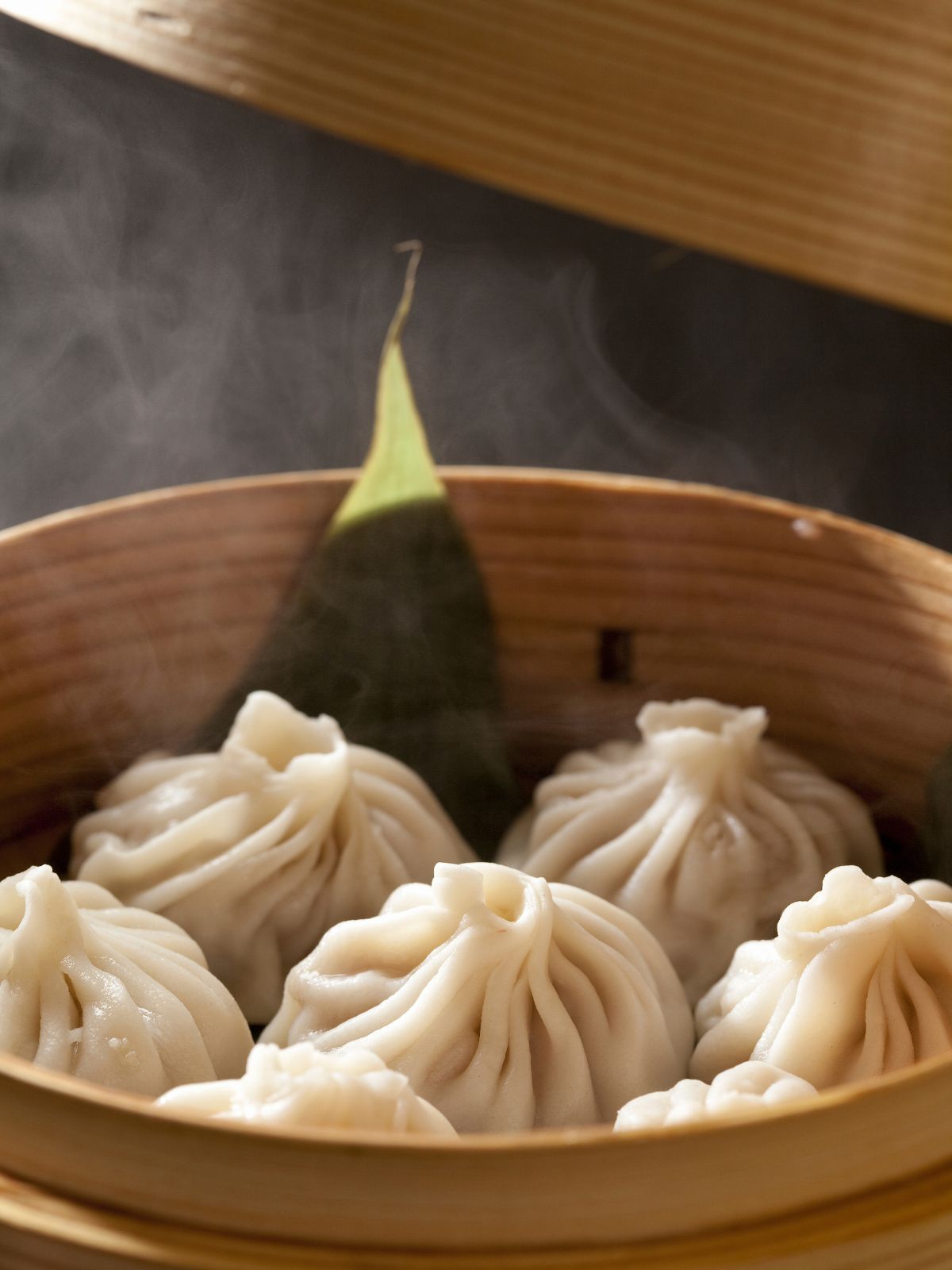 Steamy soup dumplings sitting inside bamboo steaming basket at Bk Hand Pulled Noodles, a Chinese Restaurant in Brooklyn