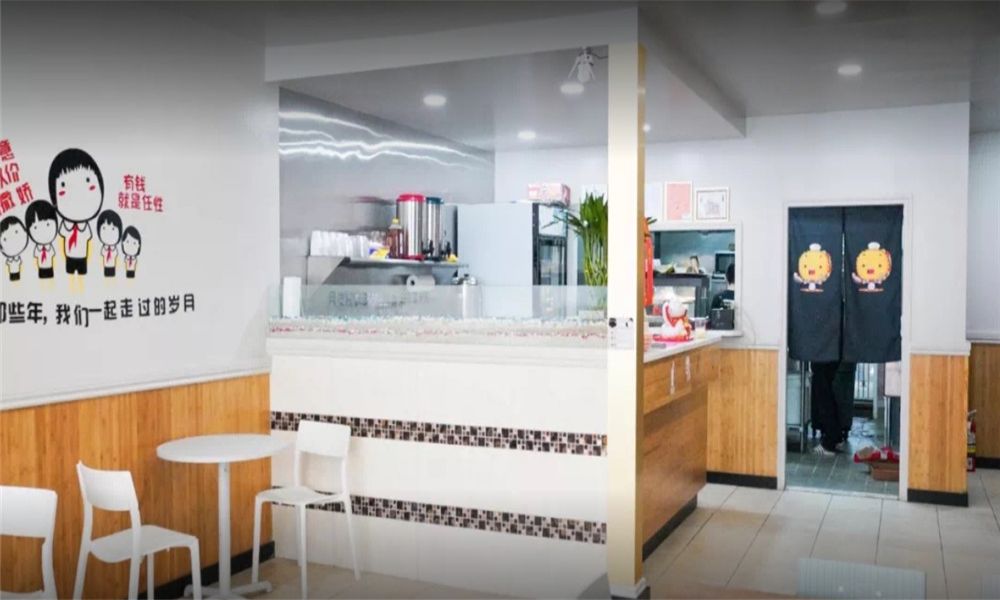 The interior of MBL&Q Burger featuring a clean counter, white tables, wooden paneling, and cartoon character wall decor at MBL&Q Burger, a Lunch Restaurant in Brooklyn