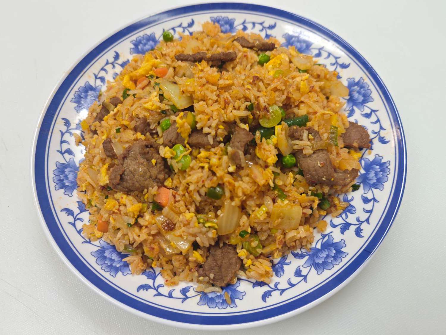 Blue & White-Fried-Rice & Noodles-Asian-Restaurant-Kimchi-Beef-Fried-Rice-Las-Vegas A plate of Kimchi Beef Fried Rice, served in a blue - and - white patterned porcelain plate. The rice is mixed with kimchi, beef slices, and vegetables, looking very appetizing at Blue & White Fried Rice & Noodles,a Asian Restaurant in Las Vegas