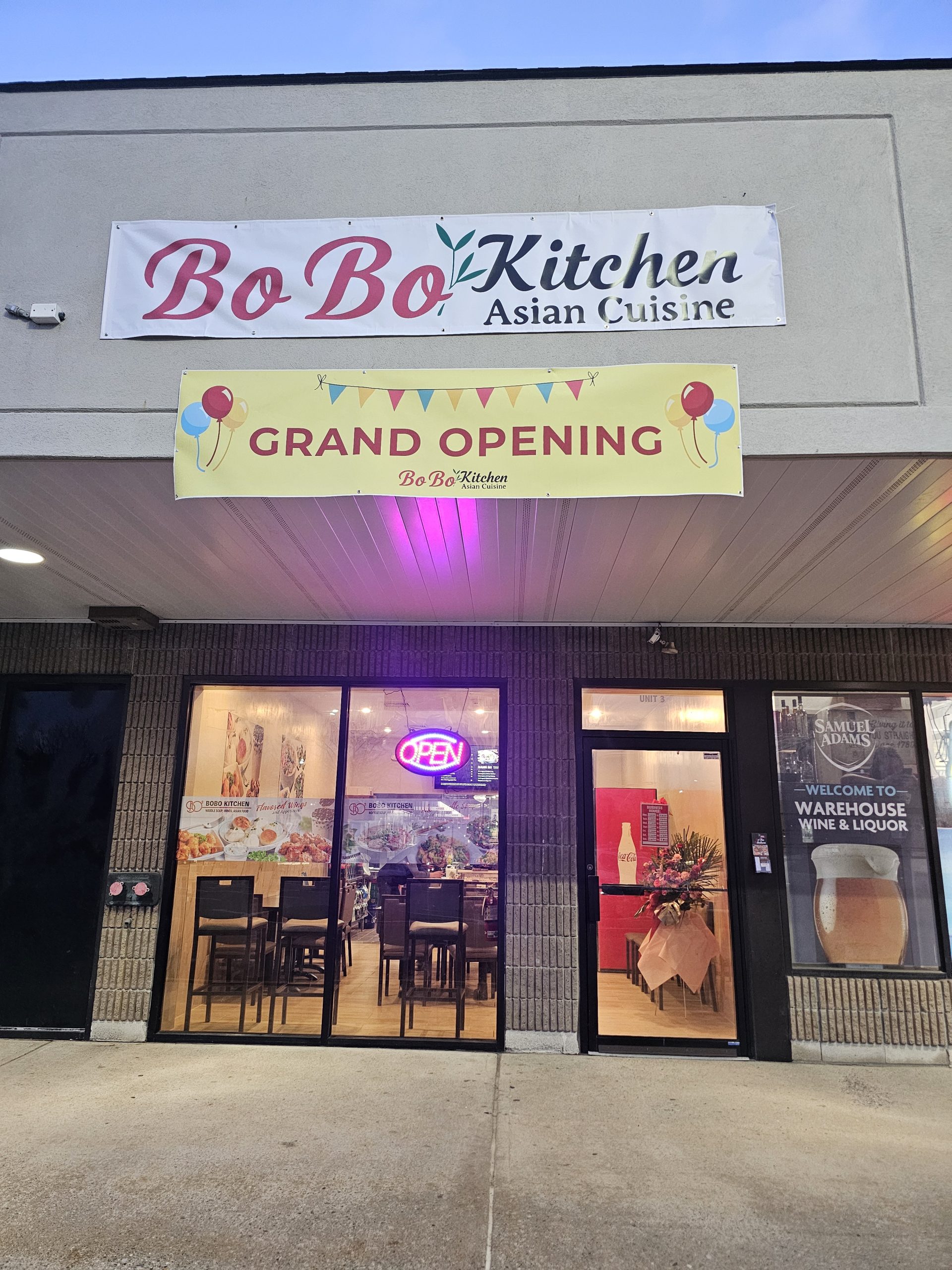 Storefront of Bo Bo Kitchen Asian Cuisine with a Grand Opening banner and neon Open sign in the window.