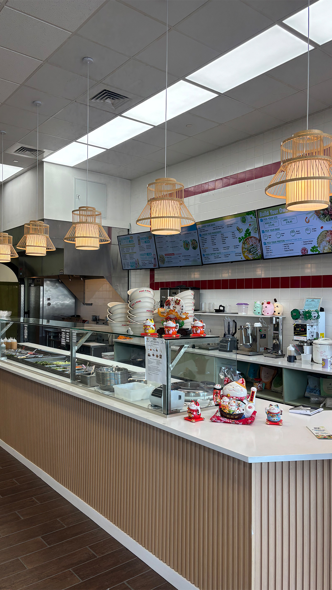 Poke-CO-2016-Bowl-Poke-Bowl-Restaurant-Bristol Modern poke restaurant counter with bamboo pendant lights, digital menu boards, and lucky cat figurines on the service bar.