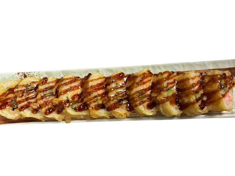 Whole deep‑fried sliced sushi roll laid flat on long narrow plate, glossy dark teriyaki sauce drizzled in stripes over golden crispy fried outer layer.