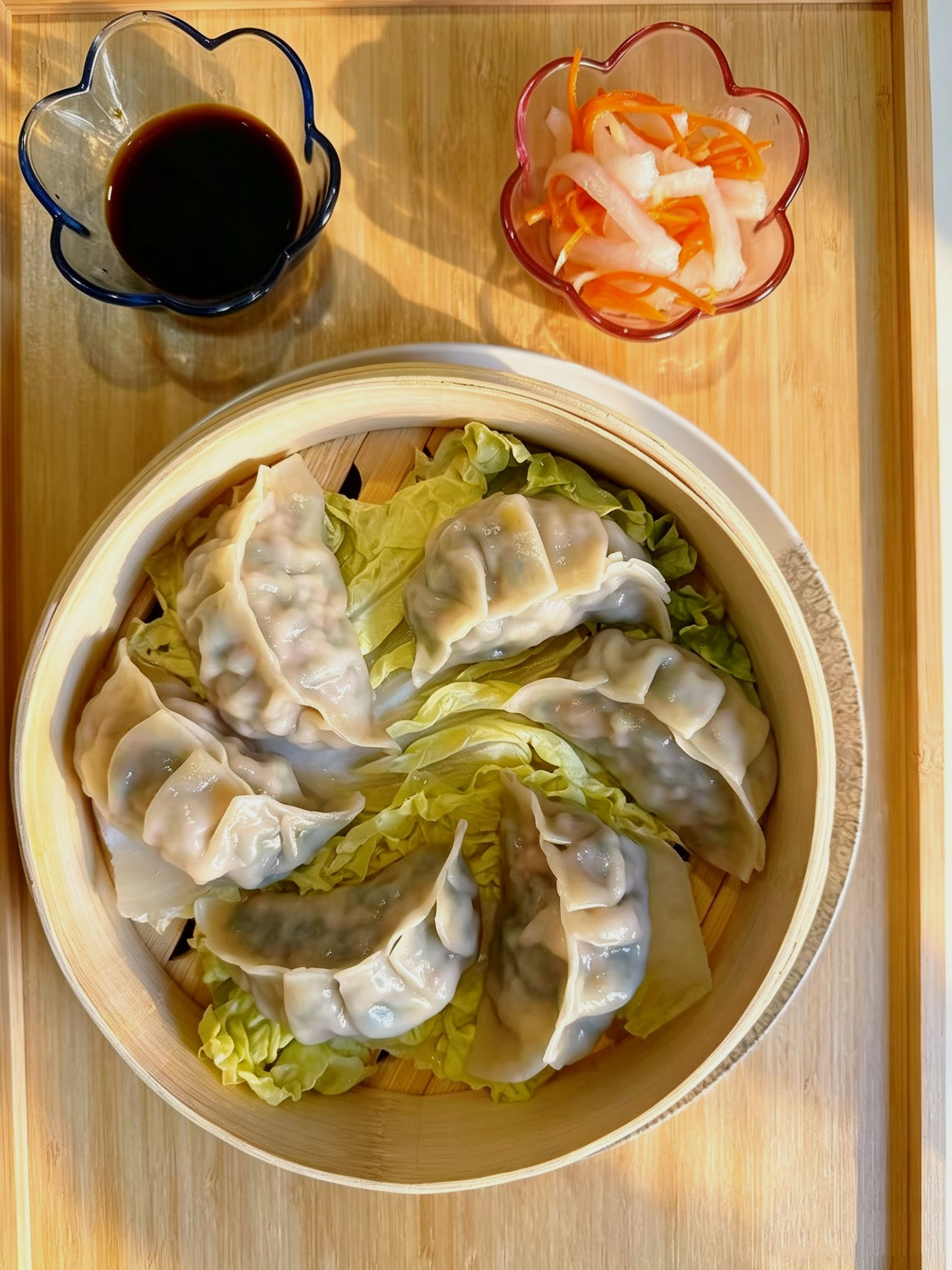 Six steamed dumplings in open bamboo steamer with soy sauce and pickled radish side at Cafe On Seneca, an Asian Fusion Restaurant in Ridgewood