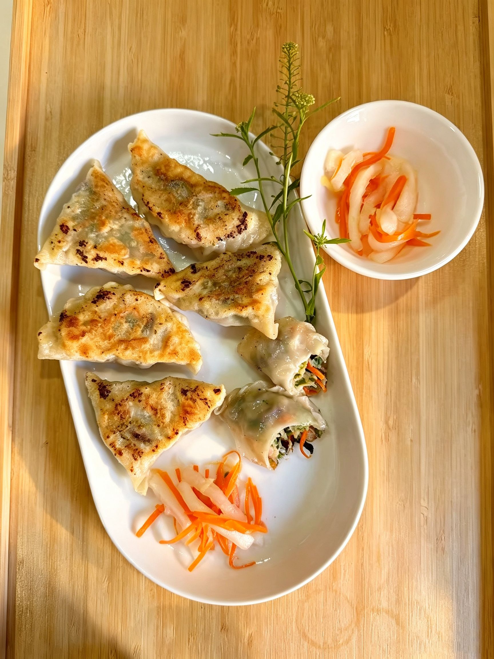 Pan-fried crispy dumplings served with pickled radish and carrot shreds on white plate at Cafe On Seneca, an Asian Fusion Restaurant in Ridgewood