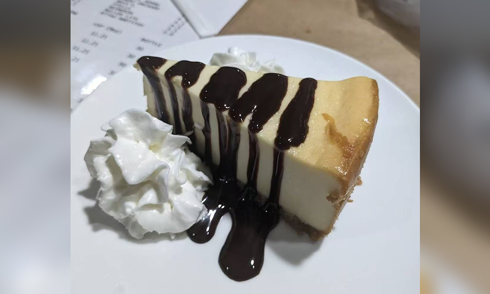 Creamy cheesecake with chocolate drizzle and whipped cream at Cajun Bros, a Seafood Restaurant in Waxahachie