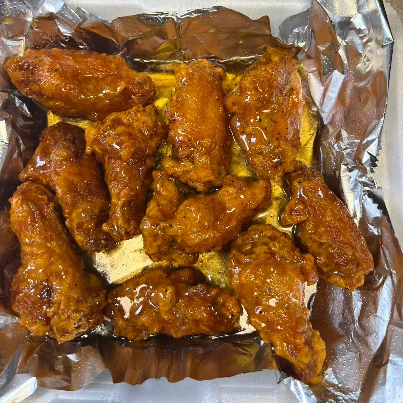 Saucy fried chicken wings served on foil at Cajun Claws & Wing, a Seafood Restaurant in Hartsville