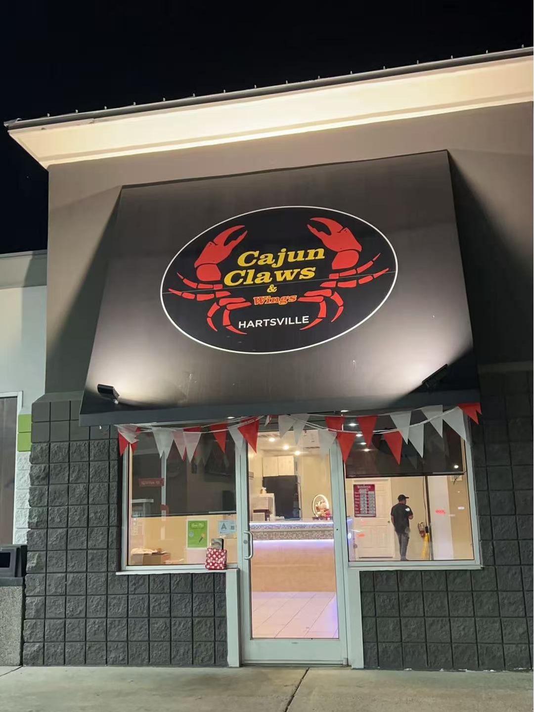 Night exterior of Cajun Claws & Wing with lit sign and bunting at Cajun Claws & Wing, a Seafood Restaurant in Hartsville